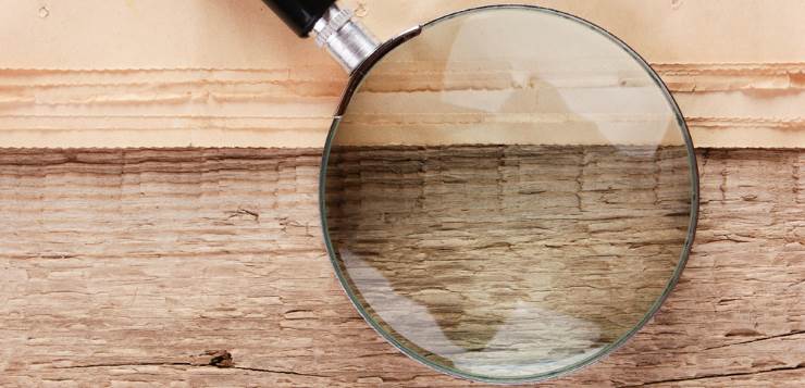edge of the old newspaper and magnifying glass on a wooden background